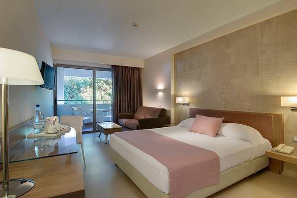 Hotelzimmer im Olympic Palace Resort mit Doppelbett, Sofa und Balkon.