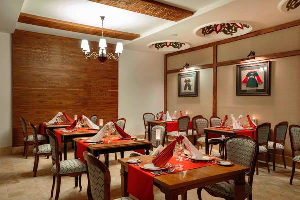 Innenansicht des Restaurants im Side Crown Palace Hotel mit dekorierten Tischen und Stühlen, Holzwänden und Deckenleuchten.