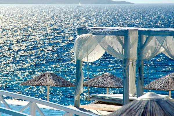 Aussicht auf das Meer vom Saint John Hotel Villas & Spa mit weißem Baldachin und Sonnenschirmen.