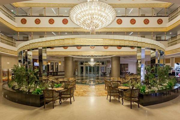 Lobby des Side Crown Palace Hotels mit einem großen Kronleuchter, gepolsterten Stühlen und runden Tischen