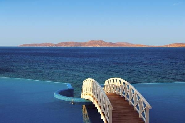 Ein Pool mit einer Brücke und Blick auf das Meer vom Saint John Hotel Villas & Spa.