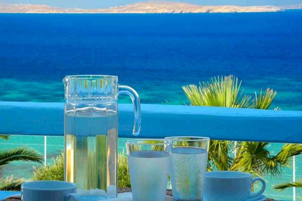 Aussicht vom Balkon des Saint John Hotels mit einer Tasse, zwei Gläsern Wasser und einer Karaffe auf dem Tisch.