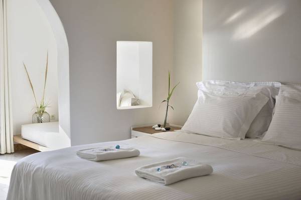 Schlafzimmer im Saint John Hotel Villas & Spa mit weißen Bettwäschen, Kissen und einem Tisch mit Pflanze