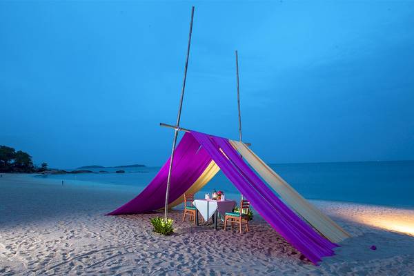 Ein Abendessen unter einem violetten und gelben Zelt auf dem Strand.