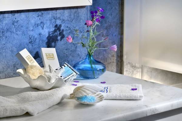 Badezimmer im Saint John Hotel Villas & Spa mit Marmortisch, Blumenvase und Handtüchern.