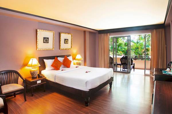 Ein Zimmer im Fair House Beach Resort mit einem Bett, Lampen und einer Terrasse.