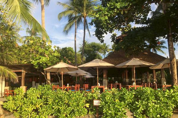 Außenbereich des Fair House Beach Resorts mit Tischen und Sonnenschirmen.