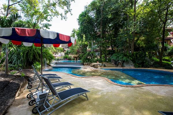 Poolbereich im Fair House Beach Resort mit Sonnenliegen und einem Schirm