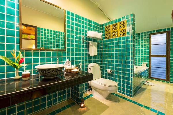 Badezimmer im Fair House Beach Resort mit türkisen Kacheln, Waschbecken, Toilette und Badewanne.