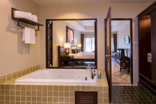 Badezimmer der Fair House Beach Resort Suite mit Badewanne, Spiegel und Ausblick auf das Schlafzimmer.