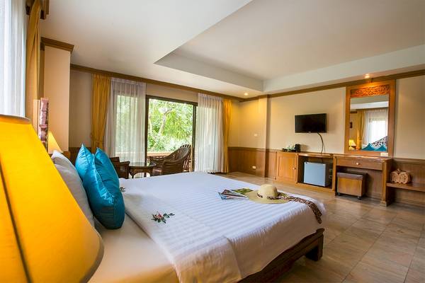 Schlafzimmer im Fair House Beach Resort mit einem Bett, Kissen, einem Hut, einem Fernseher, einem Schrank und einer Lampe.