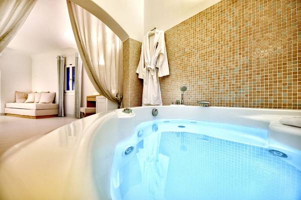 Badewanne im Badezimmer des Saint John Hotel Villas & Spa mit blau beleuchtetem Wasser