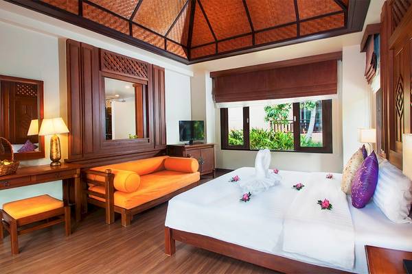 Schlafzimmer im Fair House Beach Resort mit Bett, Couch, Tisch, Fernseher und Fenster.