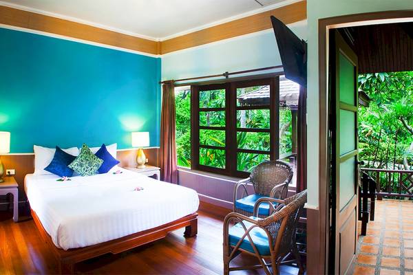 Zimmer im Fair House Beach Resort mit einem Bett, Kissen, Nachttischen und einem Balkon