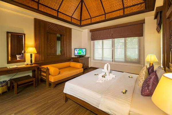 Schlafzimmer im Fair House Beach Resort mit Bett, Sofa, Fernseher und Fenstern.