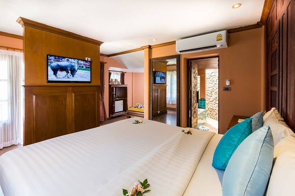 Schlafzimmer im Fair House Beach Resort mit Fernseher und Dekoblumen auf dem Bett