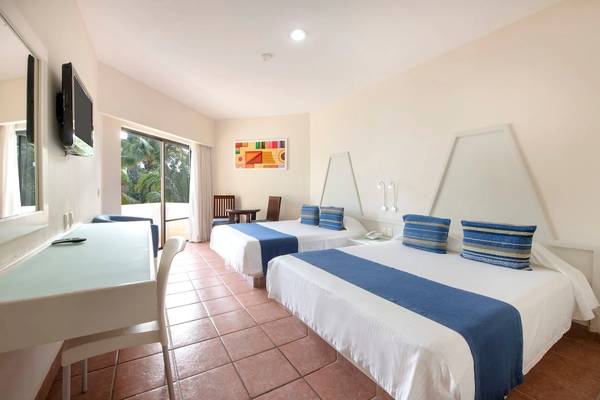 Zwei Doppelbetten in einem Hotelzimmer des Viva Wyndham Maya mit modernen Möbeln und einem Fernseher.