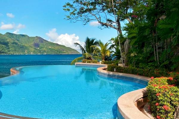 Ein Swimmingpool mit Blick auf das Meer und einen Berg im Hintergrund im Hilton Seychelles Northolme Resort & Spa.