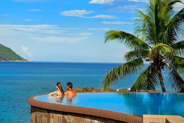 Paar im Pool mit Blick auf den Ozean und einen Berg im Hintergrund im Hilton Seychelles Northolme Resort & Spa