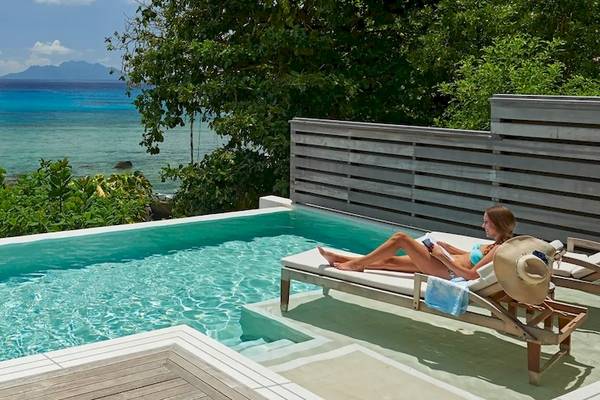 Ein Paar genießt den Swimmingpool mit Meerblick im Hilton Seychelles Northolme Resort & Spa.