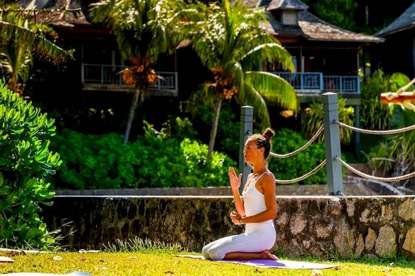 Yoga Kurs im Hilton Seychelles Northolme Resort & Spa mit Teilnehmern auf der Wiese vor einem Gebäude