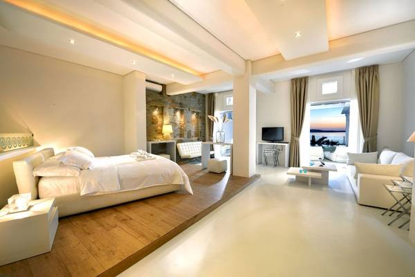 Innenansicht des Schlafzimmers im Saint John Hotel Villas & Spa mit Bett, Sofa und Aussicht.