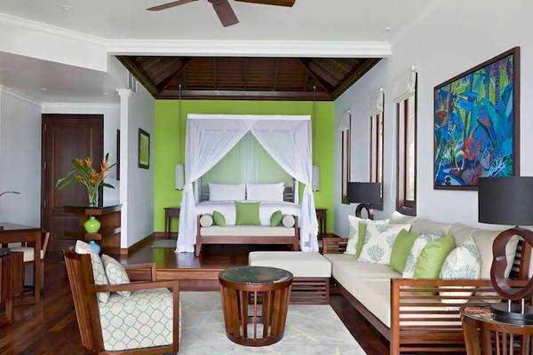 Innenraum des Hilton Seychelles Northolme Resort & Spa mit einem Bett, Fernseher und Wohnzimmermöbeln.