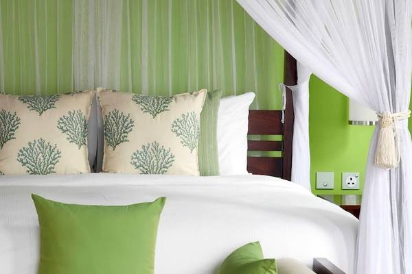 Schlafzimmer im Hilton Seychelles Northolme Resort & Spa mit grünen Wänden und weißen Vorhängen.