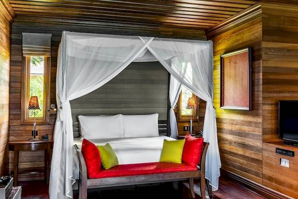 Schlafzimmer im Hilton Seychelles Northolme Resort & Spa mit einem großen Bett, einem Baldachin und einem Fernseher.