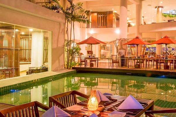 Pool-Lounge im Occidental Eden Beruwala Hotel mit roten Sonnenschirmen und Tischen.
