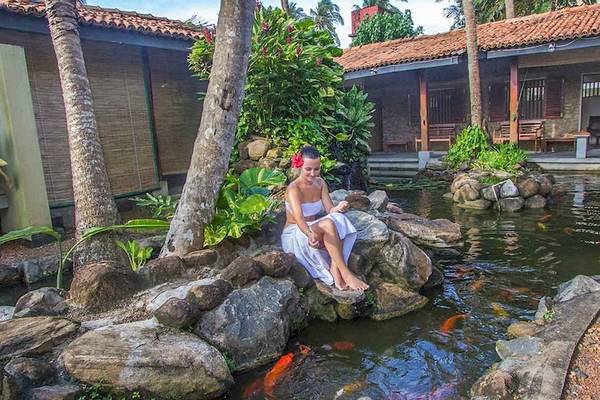 Eine Frau sitzt am Fischteich im Occidental Eden Beruwala Hotel