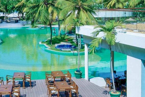 Außenpool und Terrasse des Occidental Eden Beruwala Hotels mit Tischen, Stühlen und Loungemöbeln.