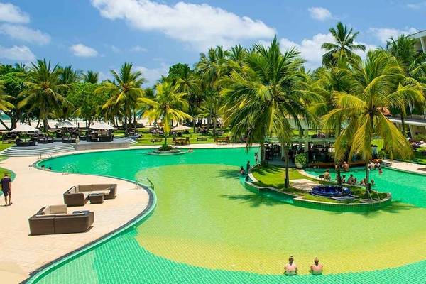 Außenansicht des Occidental Eden Beruwala Resorts mit Swimmingpool, Palmen und Hotelgebäuden.