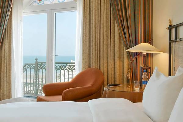 Grand Hyatt Muscat Hotelzimmer mit Meeraussicht, Bett, Stuhl, Tisch und Lampe.