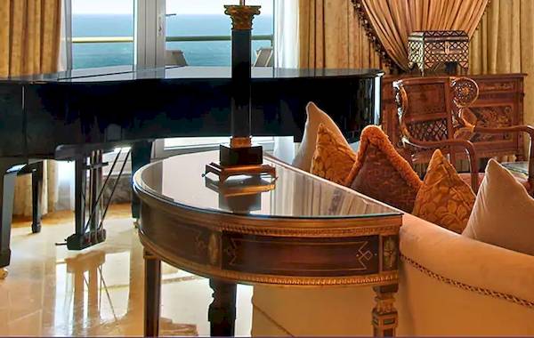 Wohnzimmer im Grand Hyatt Muscat mit Klavier, Sofa, Sessel, Tisch und Meerblick.