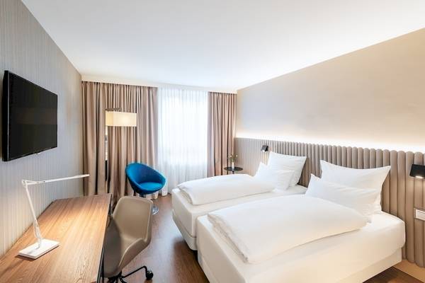 Zimmer im NH Hamburg Altona Hotel mit zwei Betten, Schreibtisch und Fernseher.