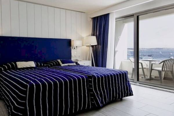 Zimmer im db Seabank Resort & Spa mit Blick auf das Meer, zwei Betten, Nachttische und Balkon.