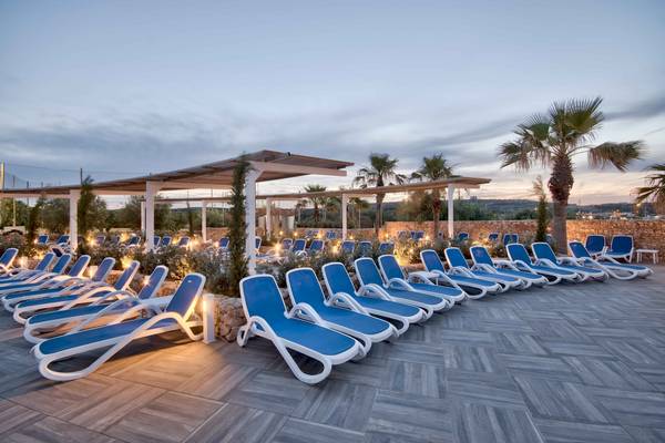 Terrasse mit Liegen im db Seabank Resort & Spa bei Sonnenuntergang