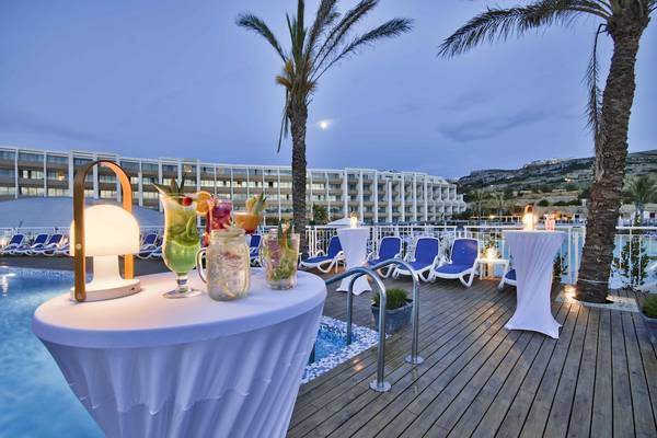 Abendliche Poolbar des db Seabank Resort & Spa mit Cocktails und Lampen.