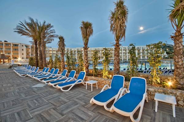 Außenbereich des db Seabank Resort & Spa mit Lounge-Stühlen und Palmen.