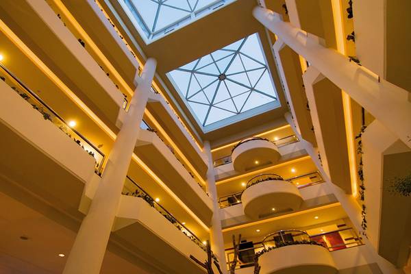 Innenansicht der Lobby des Mediterranean Beach Hotel in Zypern mit Glasdach und mehreren Stockwerken.