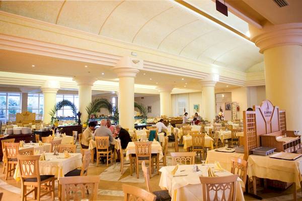Innenansicht des Restaurants im El Mouradi Hammamet Hotel mit Gästen an Tischen und Säulen.