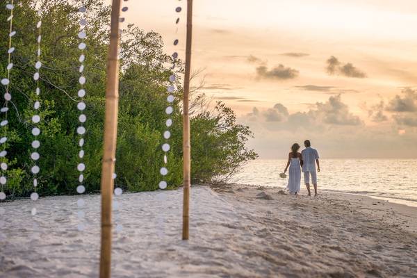 Paar auf dem Strand bei Sonnenuntergang am Malahini Kuda Bandos Resort