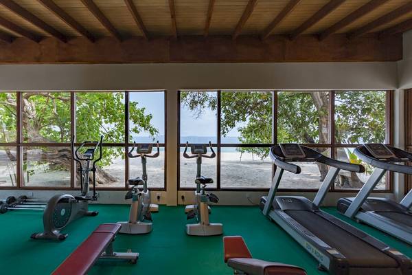 Fitnessraum mit großen Fenstern und Blick auf den Strand im Malahini Kuda Bandos Resort.