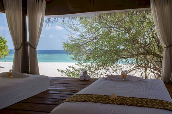 Spa-Behandlungsraum im Malahini Kuda Bandos Resort mit Blick auf den Strand und das Meer.