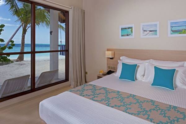 Innenansicht eines Hotelzimmers mit Meerblick, Doppelbett und drei Bildern an der Wand.