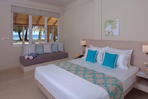 Schlafzimmer im Malahini Kuda Bandos Resort mit Blick auf das Meer.