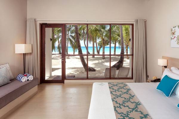 Zimmer im Malahini Kuda Bandos Resort mit Panoramafenster und Blick auf den Strand.