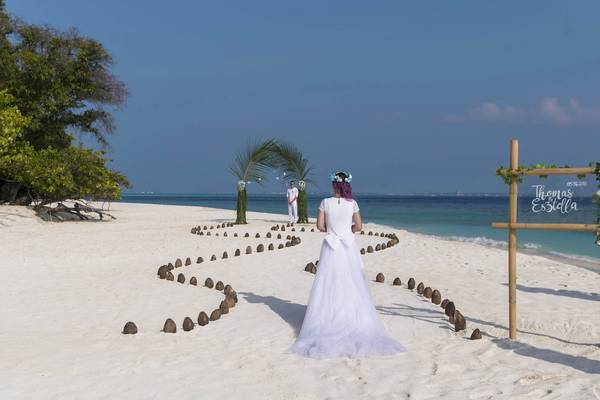 Hochzeitszeremonie am Strand des Malahini Kuda Bandos Resorts mit einem Brautpaar, das auf einem Weg aus Kokosnussschalen steht.