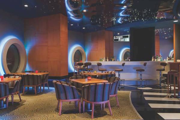 Innenansicht des Nachtclubs Ozone im Wyndham Grand Izmir Ozdilek Hotel mit gepolsterten Stühlen und einer Bar.